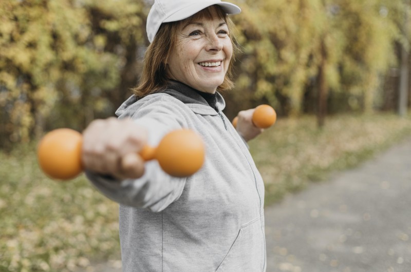 smiley elderly woman working out with weights outdoors v2